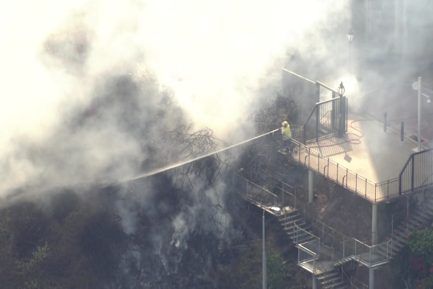 Firefighters surrounded by smoke as they stand on an outdoor staircase