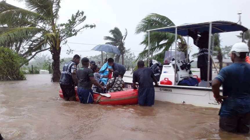 People trying to get in a rescue boat in the middle of flooding in Fiji after cycle Ana hit.