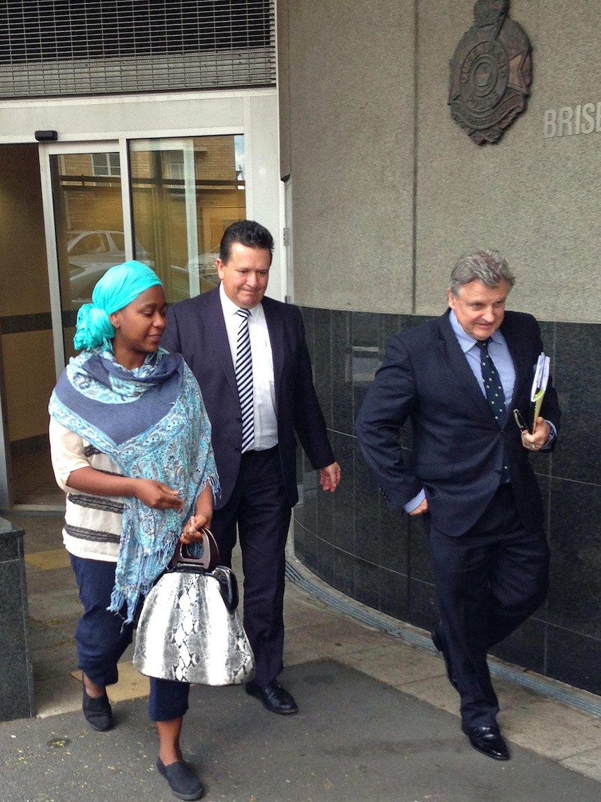 A woman walks beside two men in suits.