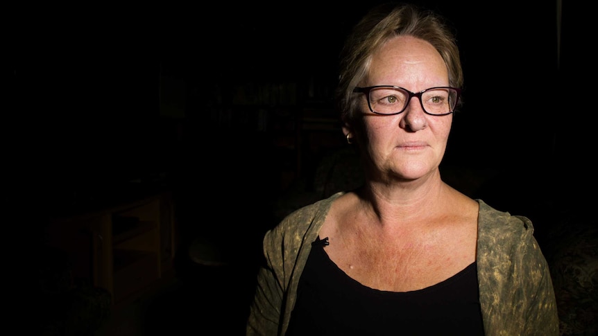 Michelle Vincent, who lost her son Nathan to suicide this year, sits in a dark room.