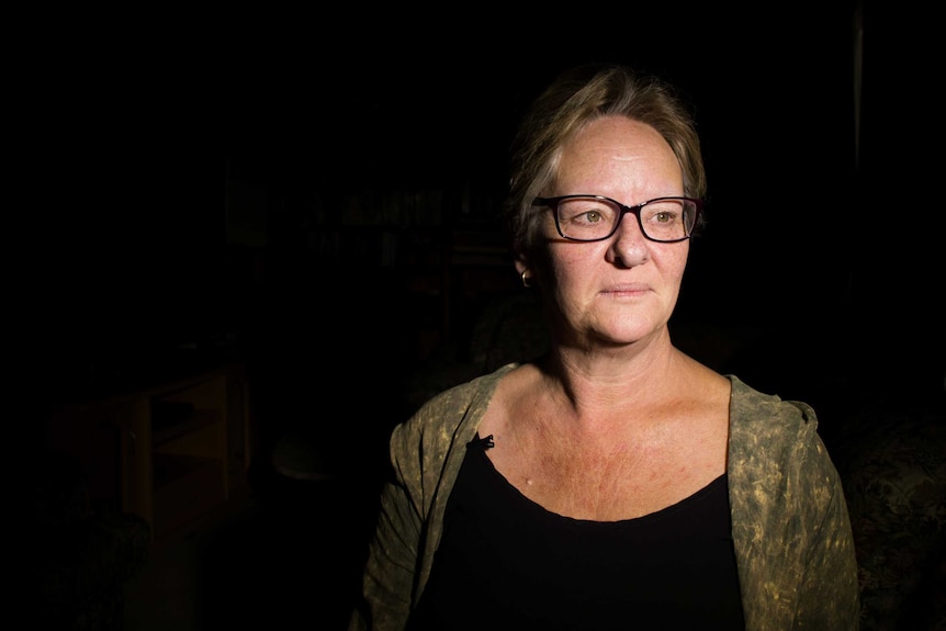 Michelle Vincent, who lost her son Nathan to suicide this year, sits in a dark room.