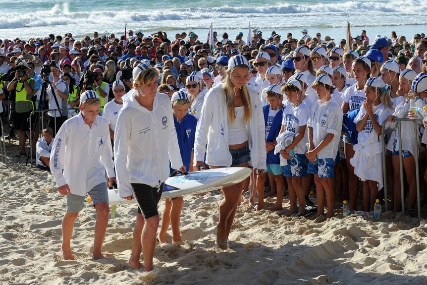 Surf life savers carry Matthew Barclay's board during a memorial service