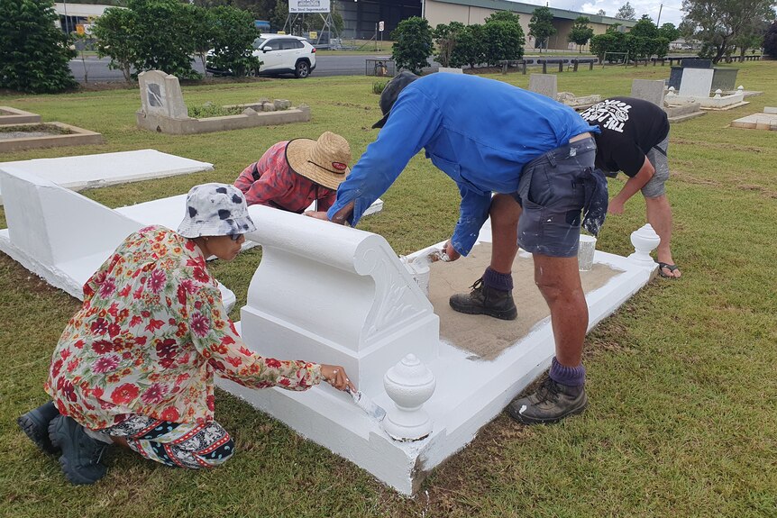people painting a grave
