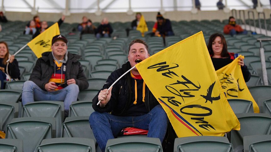 Fans wave Adelaide Crows flags at the AFL Showdown against Port Adelaide.
