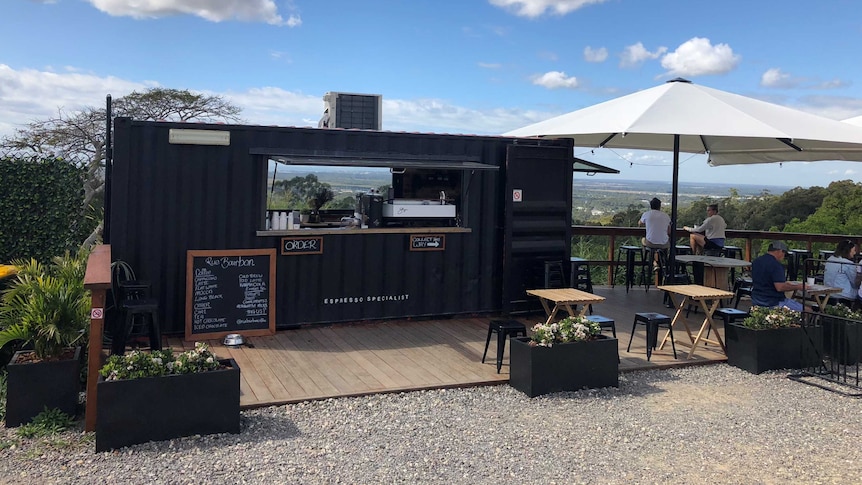 People sit outside a shipping container being used as a cafe.