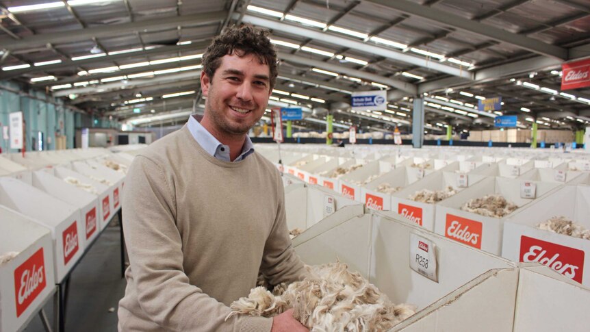 Man smiling look at white wool in a big shed