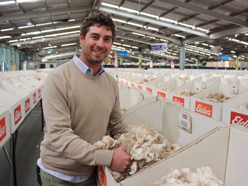 Man smiling look at white wool in a big shed