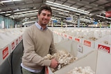 Man smiling look at white wool in a big shed