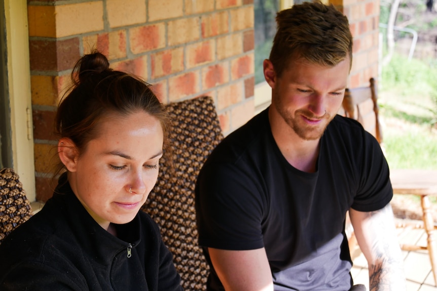 A young woman and man sitting on their verandah