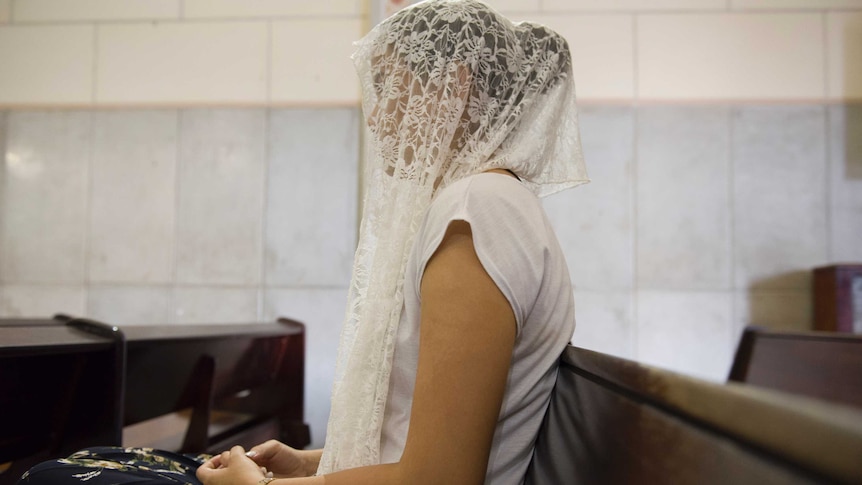 Woman wearing white veil praying at Church