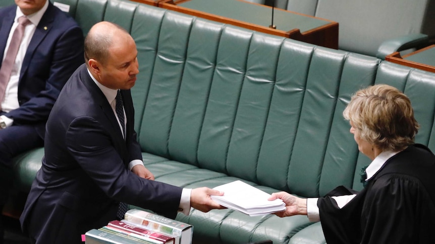 Josh Frydenberg hands a bundle of papers to the clerk.