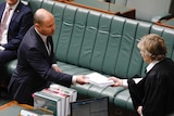 Josh Frydenberg hands a bundle of papers to the clerk.