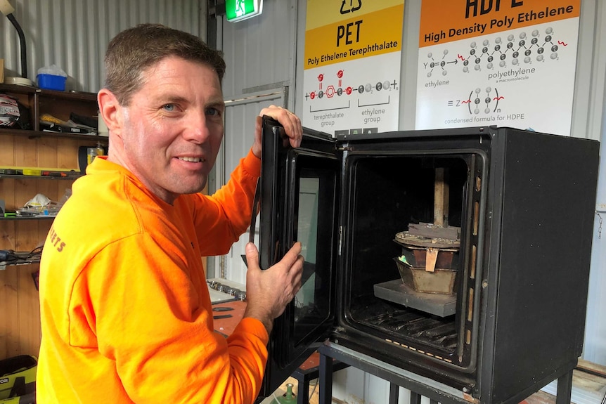 Brad Scott stands with the recycling machinery he built with scrap items.