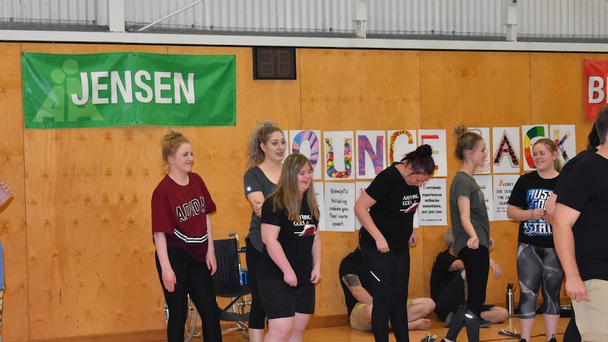 A short lady with blonde hair is centre shot, with other women around her. She is laughing.