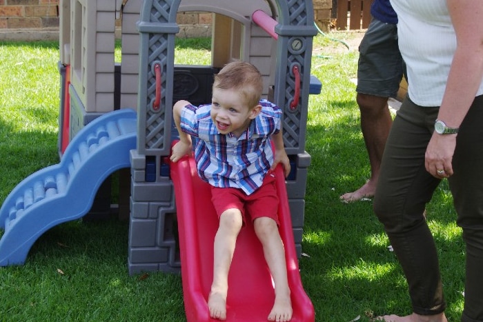 A little boy on a slide.