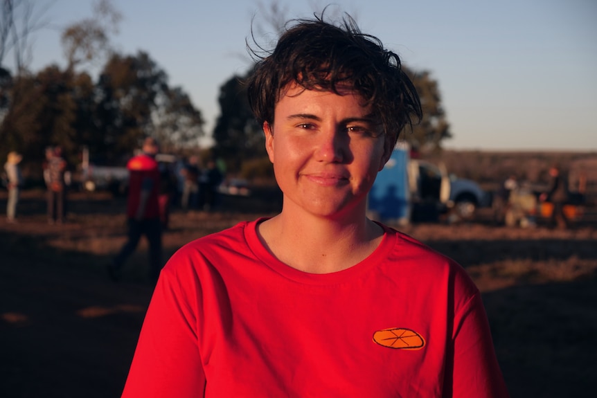 A woman with short dark hair and a red t-shirt smiles.