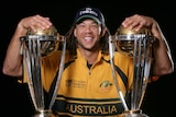 Andrew Symonds smiles while posing with two World Cup trophies