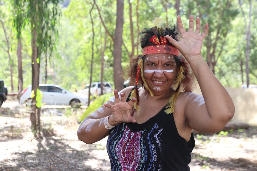 Woman dressed in bright colours, cultural body paint and headress.