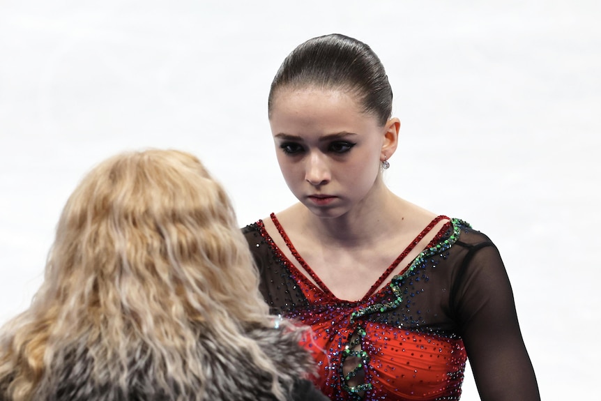 A young girl talks to a woman with wavy blonde hair.