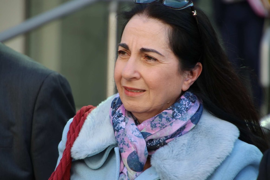 A woman in a sky blue coat and colourful scarf outside court.