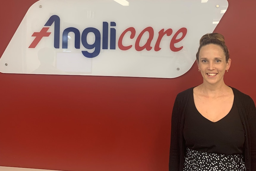 Woman in black shirt standing in front of Anglicare sign