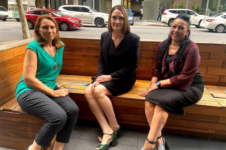 Three women sit on a bench.