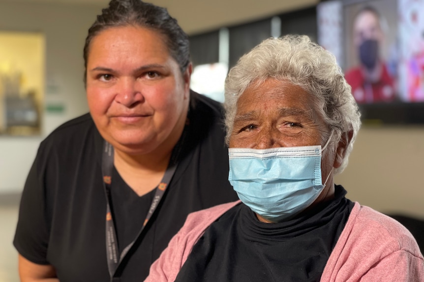 An Indigenous woman and her middle aged daughter pose for the camera.