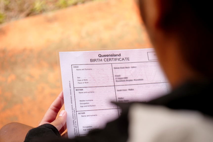 An over the shoulder shot of a person holding a Queensland Birth Certificate.