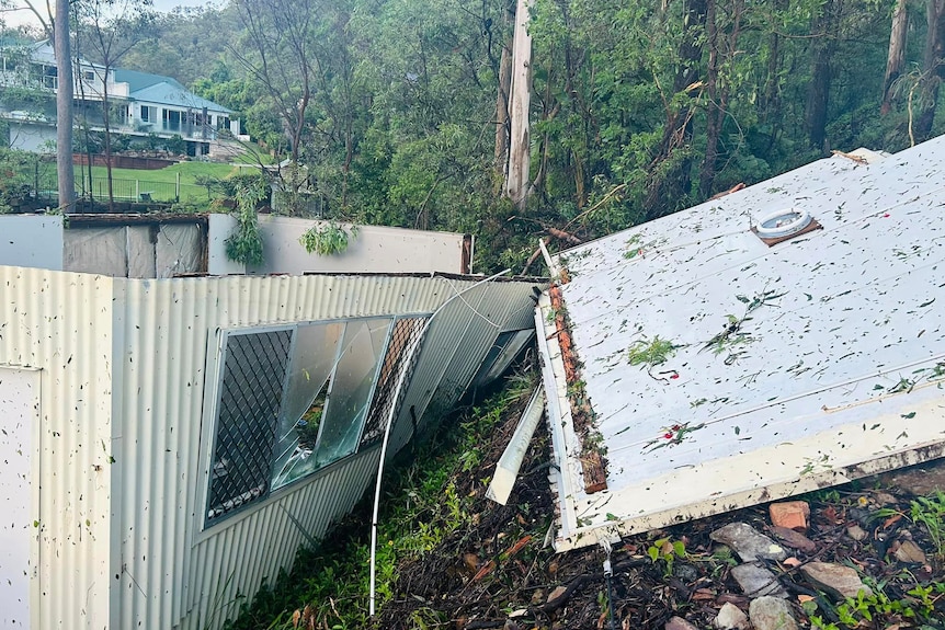 A side shot of a shed with the roof ripped off.