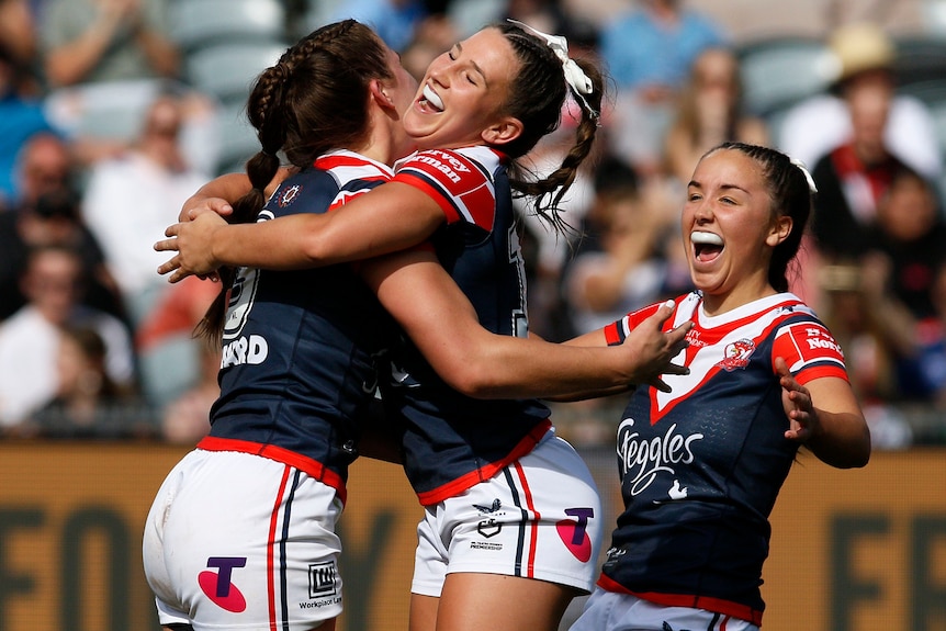 Three Sydney Roosters NRLW players embrace as they celebrate a try.