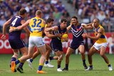 Jaeger O'Meara carries the ball in the middle of a group of players