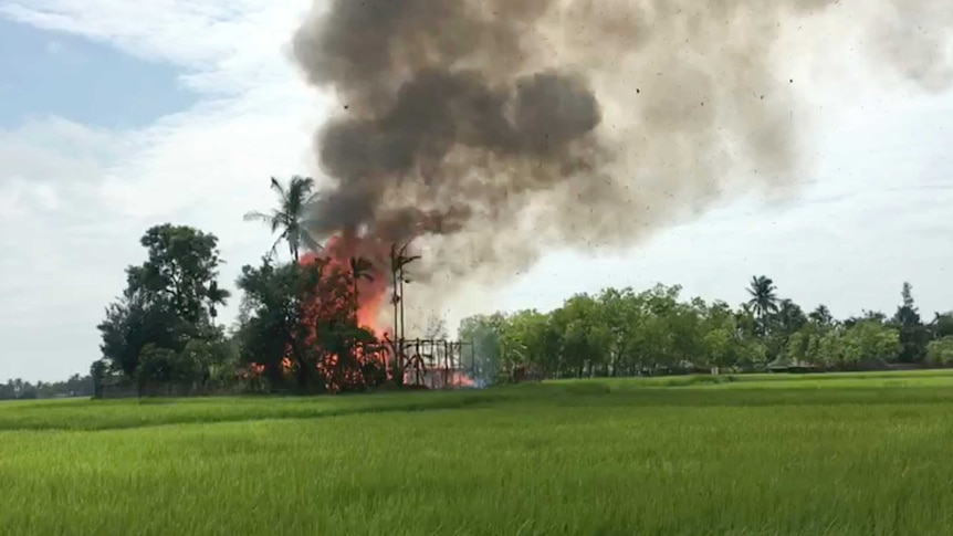 Fire and smoke can be seen as a building burns in the distance.