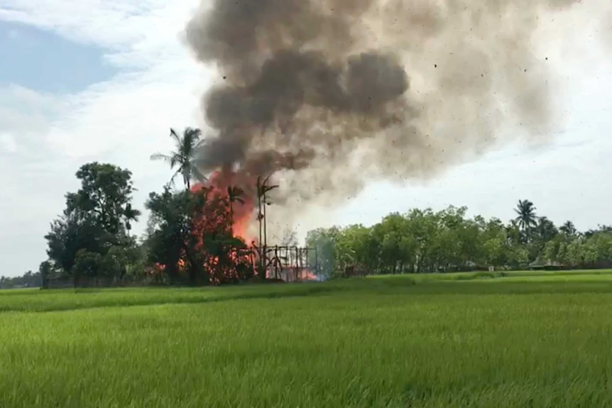 Fire and smoke can be seen as a building burns in the distance.