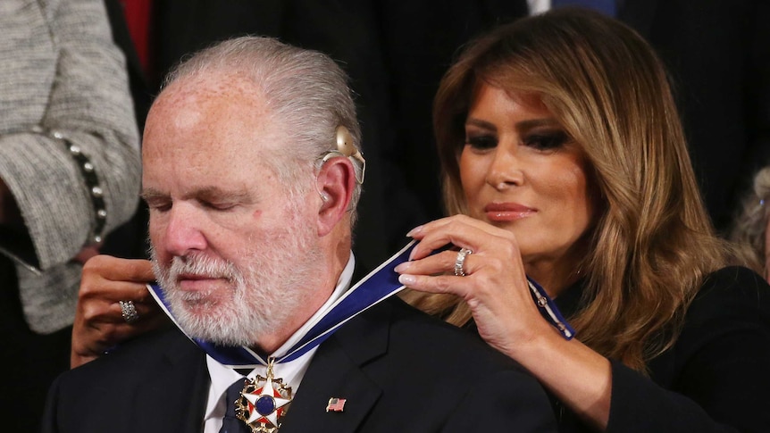Right wing radio host Rush Limbaugh closes his eyes as FLOTUS pins the medal of freedom around his neck
