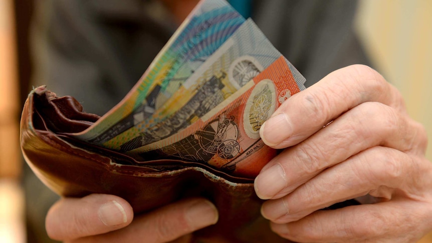 Hands holding a wallet with bank notes sticking out