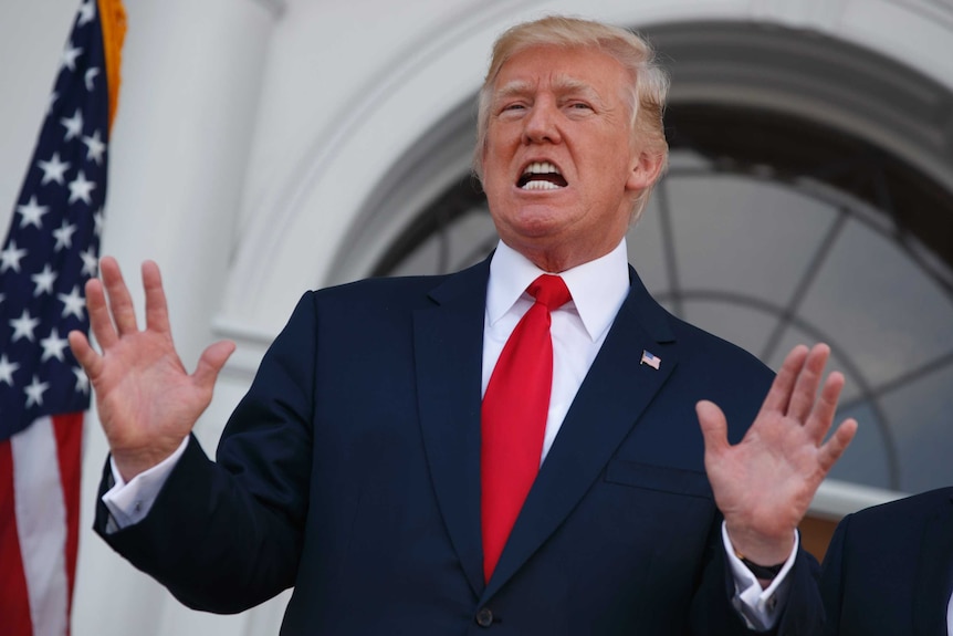 President Donald Trump speaks to reporters with his hands in the air.