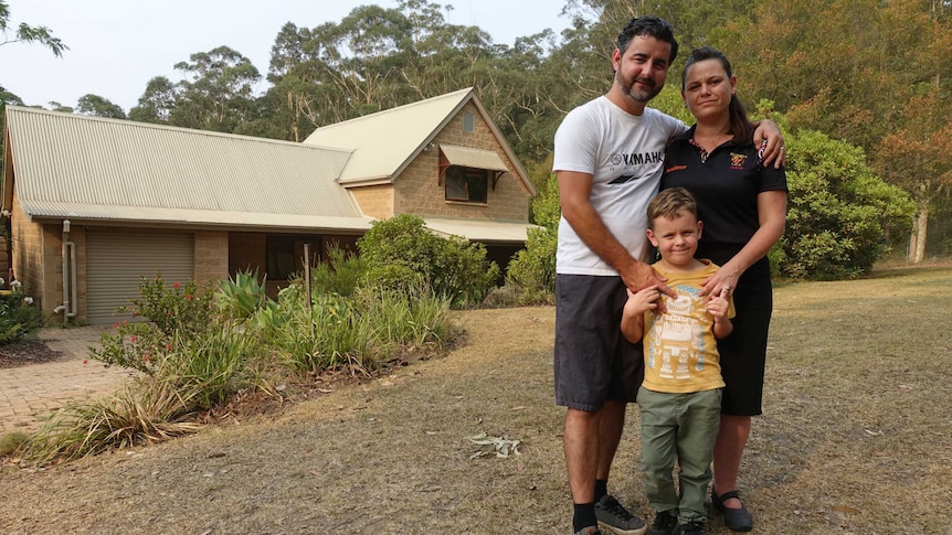 A family holding each other in front of a home.