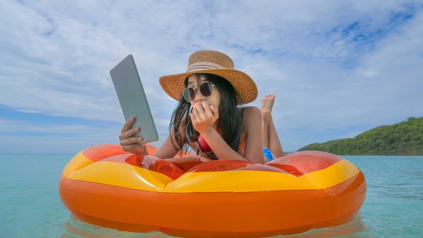 A woman reads from an ebook on an orange float.