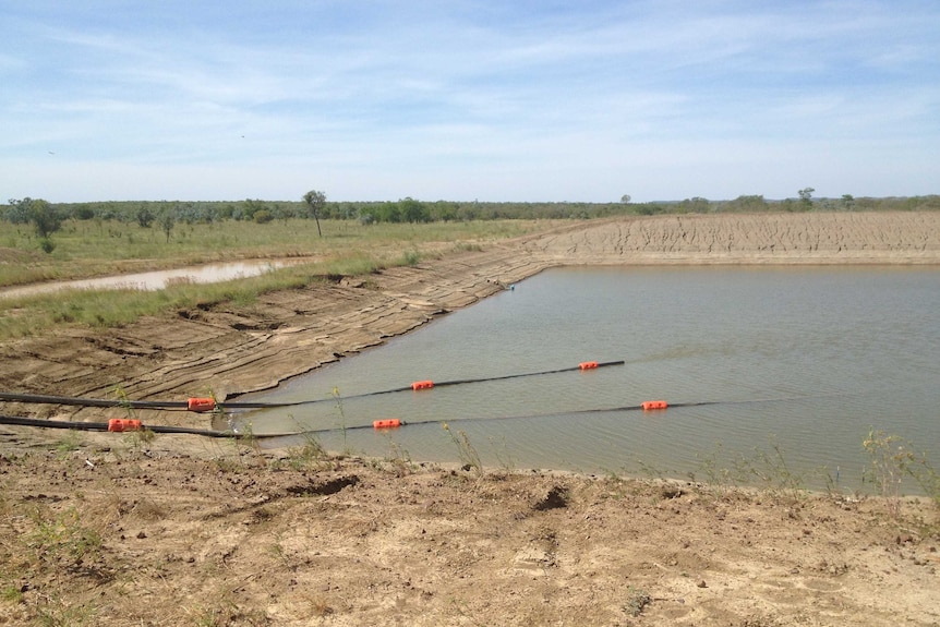 A square, man made dam with water in it.