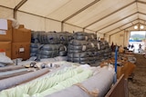 A large white tent filled with boxes of donated goods.