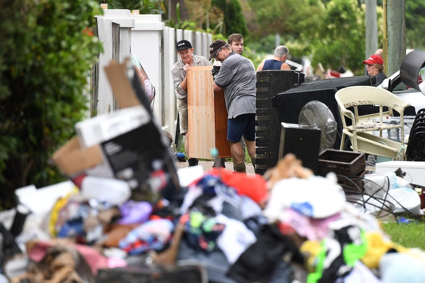 People clearing out flood-damaged items from homes in Townsville