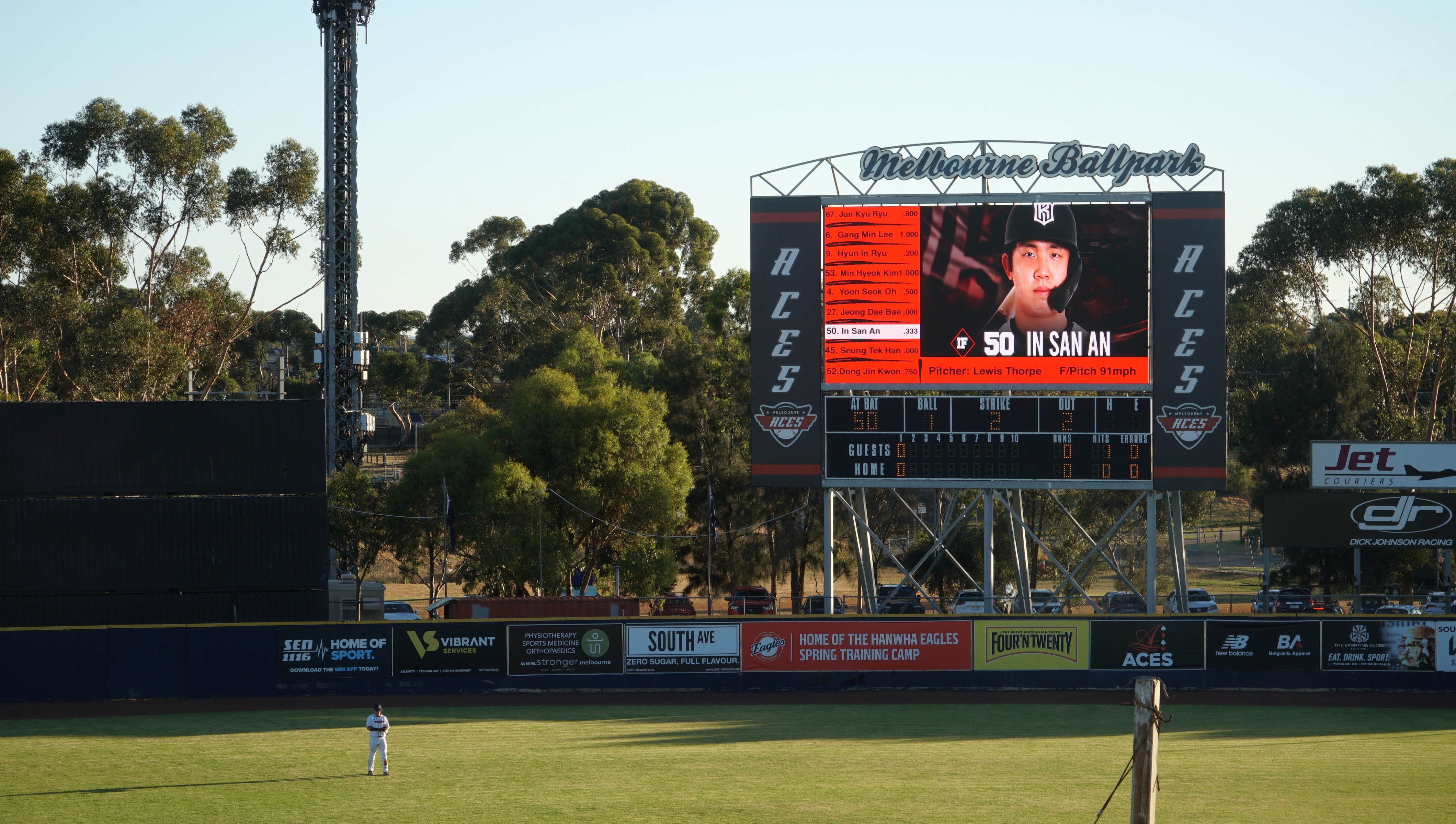 Uma foto ampla de um estádio de beisebol brilhante e ensolarado.