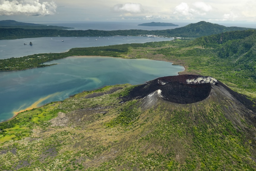 Ash covered volcano crater with ocean view in the background. 