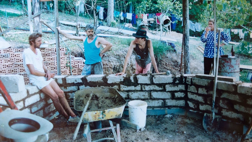 Four people build a brick wall outside