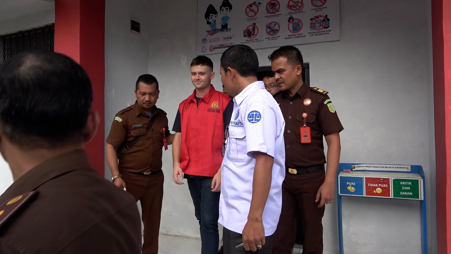 A man stands between two Indonesian police officers