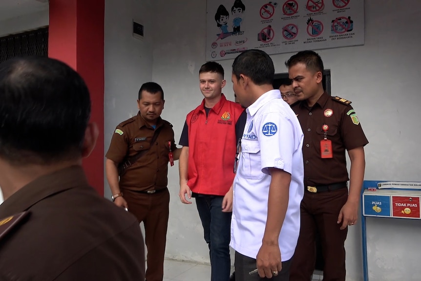 A man stands between two Indonesian police officers