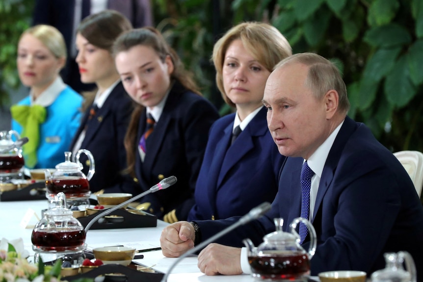 Russian President Vladimir Putin speaks at table.