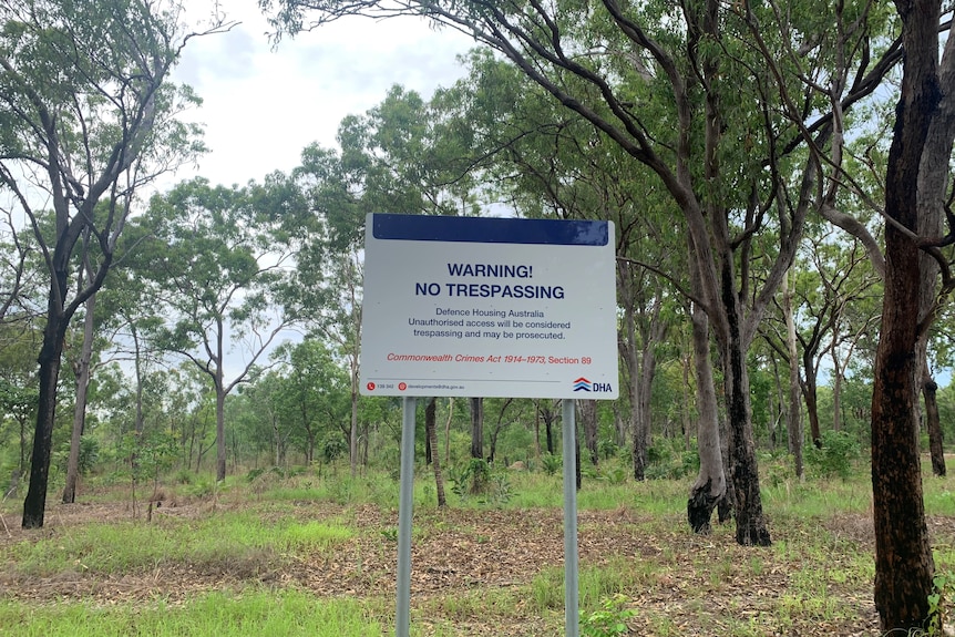 A sign among trees warning trespassers to stay away because of a planned housing development in the area.