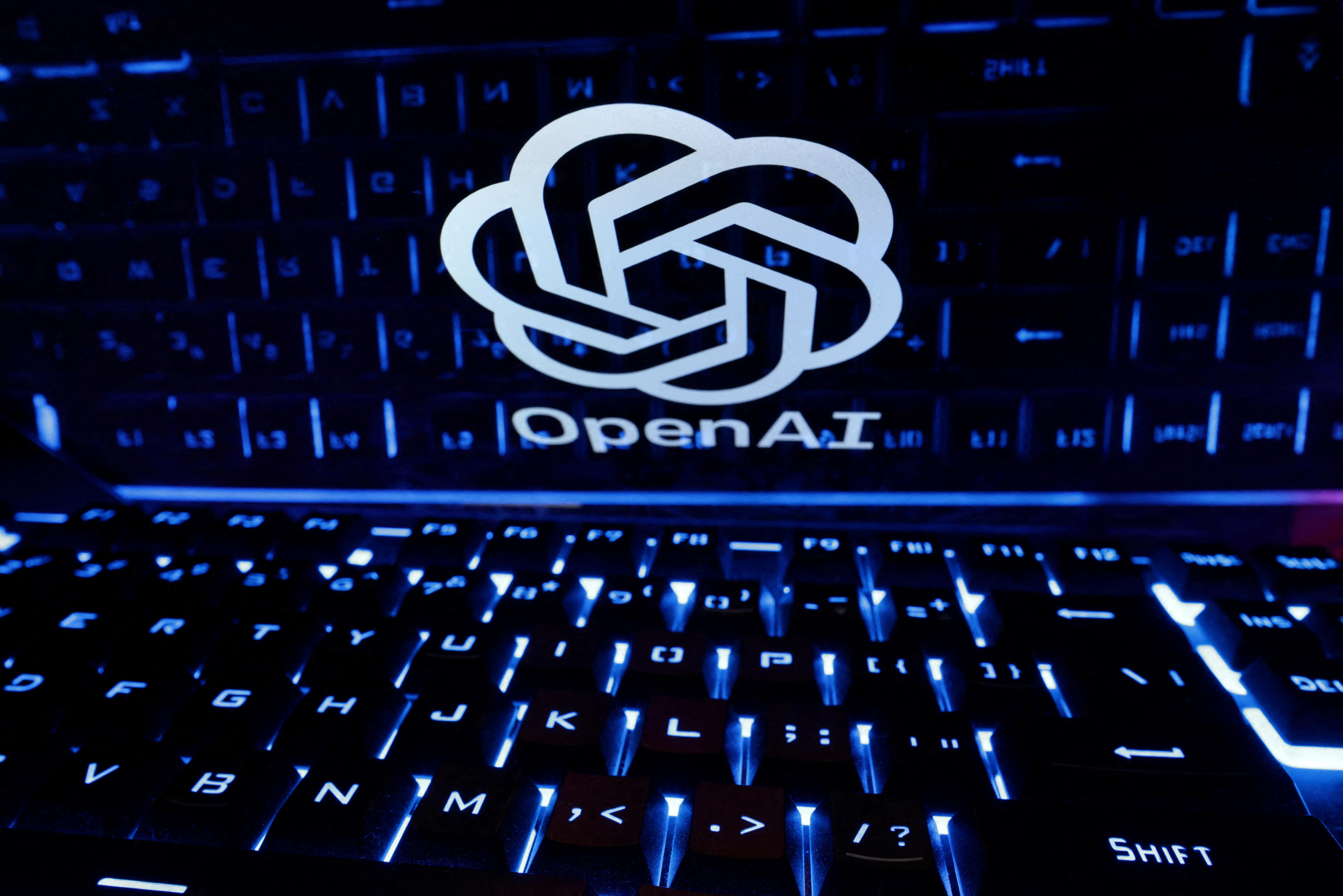 A circular white logo on the screen of a laptop shrouded in darkness.