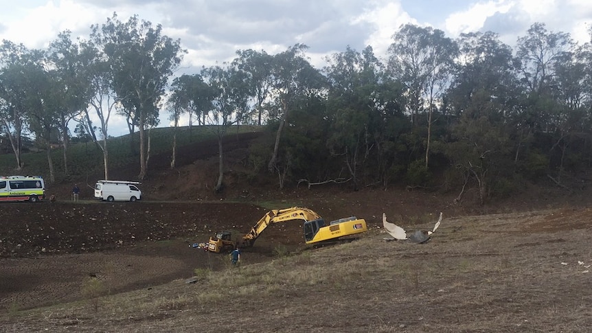 An excavator at a Toowoomba property near a dam.